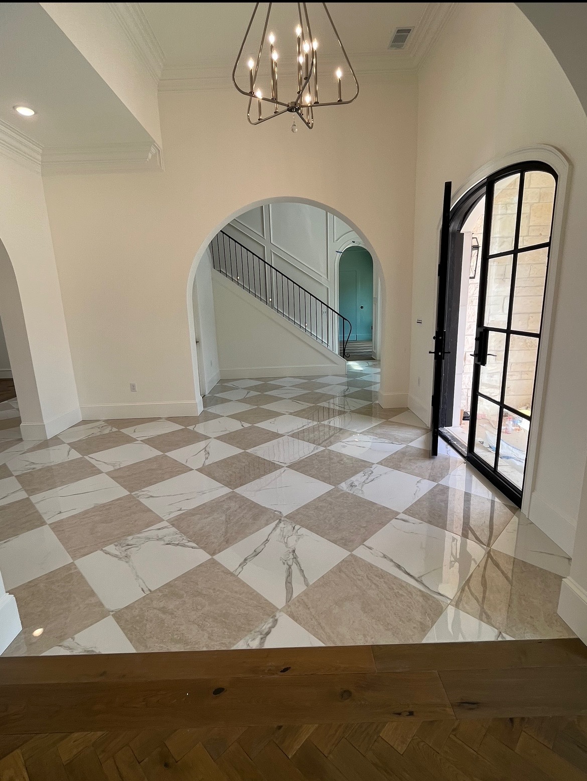 Marble checkered foyer with arched iron door and chandelier